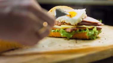 Şef, Fransız ekmeği, peynir, marul ve sosis ile sanvich 'in üzerinde kaynayan bir kalp şeklinde yumurta sarısı şeklinde bir çatalla ezer. Kaydırıcı atışı.