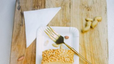 Altın çatallı bir tabakta fıstıklı kek. Arka planda retro-stil yemek tepsisi üzerinde soyulmuş fıstık var. Makro ve sürgülü atış.