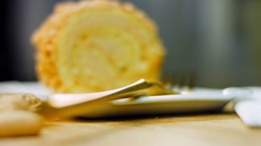 Altın çatallı bir tabakta fıstıklı kek. Arka planda retro-stil yemek tepsisi üzerinde soyulmuş fıstık var. Makro ve sürgülü atış.