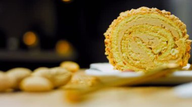 Altın çatallı bir tabakta fıstıklı kek. Arka planda retro-stil yemek tepsisi üzerinde soyulmuş fıstık var. Makro ve sürgülü atış.