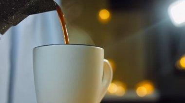 Kadın bardağa taze demlenmiş kahve dolduruyor. Kahve makinesinde kahve demleme işlemi. Romantik ambiyans ve makro çekim..