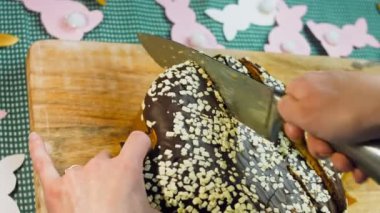 Kadın çikolatalı keki bıçakla keser. Arka planda kağıttan yapılmış Paskalya arınmaları var. Makro ve sürgülü atış.