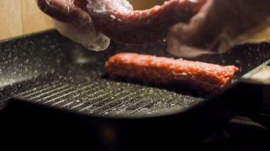 Aşçı ızgara tavasında pembe sosisleri kızartır. Sosisler sıraya dizildi. Kaydırıcı atışı.