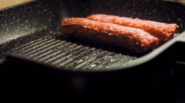 Aşçı ızgara tavasında pembe sosisleri kızartır. Sosisler sıraya dizildi. Kaydırıcı atışı.