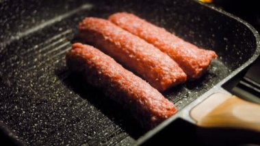 Aşçı ızgara tavasında pembe sosisleri kızartır. Sosisler sıraya dizildi. Kaydırıcı atışı.