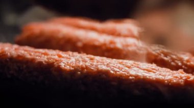 Pembe sosisler ızgara tavasında kızartılır. Sosisler sıraya dizildi. Sosisler buhar oldu. Kaydırıcı atışı.