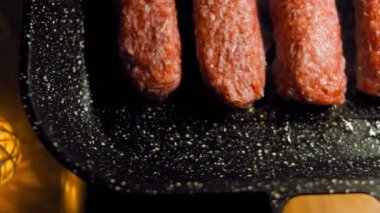 Pembe sosisler ızgara tavasında kızartılır. Sosisler sıraya dizildi. Sosisler buhar oldu. Kaydırıcı atışı.