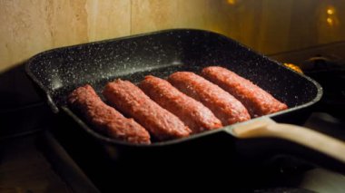 Aşçı ızgara tavasında pembe sosisleri kızartır. Sosisler sıraya dizildi. Kaydırıcı atışı.