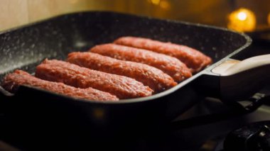 Aşçı ızgara tavasında pembe sosisleri kızartır. Sosisler sıraya dizildi. Kaydırıcı atışı.