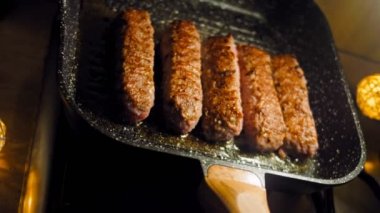 Pembe sosisler ızgara tavasında kızartılır. Sosisler sıraya dizildi. Sosisler buhar oldu. Kaydırıcı atışı.