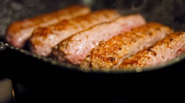 Pembe sosisler ızgara tavasında kızartılır. Sosisler sıraya dizildi. Sosisler buhar oldu. Kaydırıcı atışı.