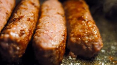 Pembe sosisler ızgara tavasında kızartılır. Sosisler sıraya dizildi. Sosisler buhar oldu. Kaydırıcı atışı.