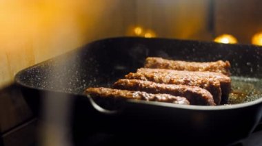 Pembe sosisler ızgara tavasında kızartılır. Sosisler sıraya dizildi. Sosisler buhar oldu. Kaydırıcı atışı.