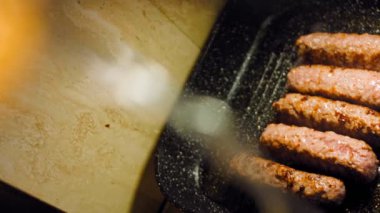 Pembe sosisler ızgara tavasında kızartılır. Sosisler sıraya dizildi. Sosisler buhar oldu. Kaydırıcı atışı.