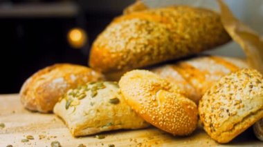 Ahşap masada farklı türde taze ekmek. Kahverengi arka planda münferit bir ekmek çeşidi. Kaydırıcı atışı.