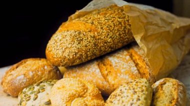 Ahşap masada farklı türde taze ekmek. Kahverengi arka planda münferit bir ekmek çeşidi. Kaydırıcı atışı.