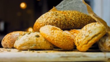 Ahşap masada farklı türde taze ekmek. Kahverengi arka planda münferit bir ekmek çeşidi. Kaydırıcı atışı.