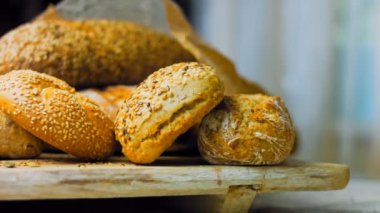 Ahşap masada farklı türde taze ekmek. Kahverengi arka planda münferit bir ekmek çeşidi. Kaydırıcı atışı.