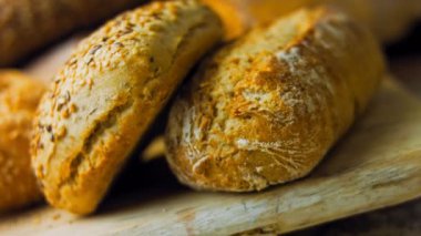 Ahşap masada farklı türde taze ekmek. Kahverengi arka planda münferit bir ekmek çeşidi. Kaydırıcı atışı.