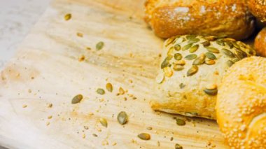 Ahşap masada farklı türde taze ekmek. Kahverengi arka planda münferit bir ekmek çeşidi. Kaydırıcı atışı.