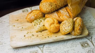 Ahşap masada farklı türde taze ekmek. Kahverengi arka planda münferit bir ekmek çeşidi. Kaydırıcı atışı.