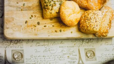 Ahşap masada farklı türde taze ekmek. Kahverengi arka planda münferit bir ekmek çeşidi. Kaydırıcı atışı.