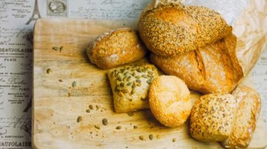 Ahşap masada farklı türde taze ekmek. Kahverengi arka planda münferit bir ekmek çeşidi. Kaydırıcı atışı.