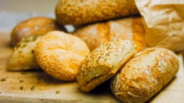 Ahşap masada farklı türde taze ekmek. Kahverengi arka planda münferit bir ekmek çeşidi. Kaydırıcı atışı.