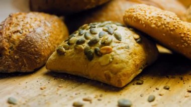 Ahşap masada farklı türde taze ekmek. Kahverengi arka planda münferit bir ekmek çeşidi. Kaydırıcı atışı.