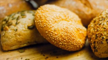 Ahşap masada farklı türde taze ekmek. Kahverengi arka planda münferit bir ekmek çeşidi. Kaydırıcı atışı.