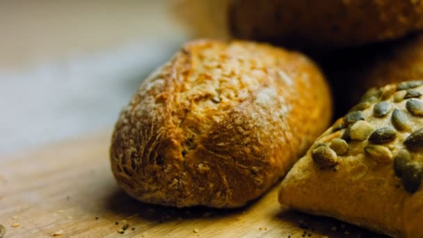 木製のテーブルの上に新鮮なパンの異なる種類 茶色の背景にパンの隔離された品揃え スライダーシュート — ストック動画