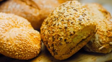 Ahşap masada farklı türde taze ekmek. Kahverengi arka planda münferit bir ekmek çeşidi. Kaydırıcı atışı.