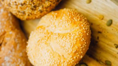 Ahşap masada farklı türde taze ekmek. Kahverengi arka planda münferit bir ekmek çeşidi. Kaydırıcı atışı.