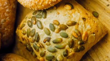 Ahşap masada farklı türde taze ekmek. Kahverengi arka planda münferit bir ekmek çeşidi. Kaydırıcı atışı.