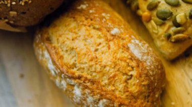 Ahşap masada farklı türde taze ekmek. Kahverengi arka planda münferit bir ekmek çeşidi. Kaydırıcı atışı.