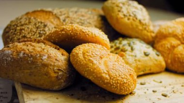 Ahşap masada farklı türde taze ekmek. Kahverengi arka planda münferit bir ekmek çeşidi. Kaydırıcı atışı.