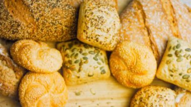 Ahşap masada farklı türde taze ekmek. Kahverengi arka planda münferit bir ekmek çeşidi. Kaydırıcı atışı.