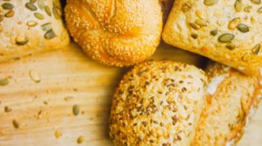 Ahşap masada farklı türde taze ekmek. Kahverengi arka planda münferit bir ekmek çeşidi. Kaydırıcı atışı.