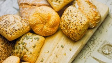 Ahşap masada farklı türde taze ekmek. Kahverengi arka planda münferit bir ekmek çeşidi. Kaydırıcı atışı.