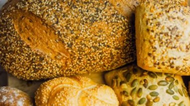 Ahşap masada farklı türde taze ekmek. Kahverengi arka planda münferit bir ekmek çeşidi. Kaydırıcı atışı.