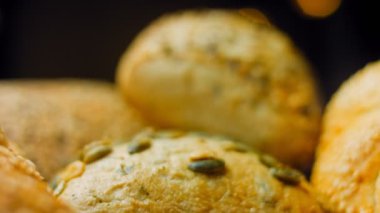Ahşap masada farklı türde taze ekmek. Kahverengi arka planda münferit bir ekmek çeşidi. Kaydırıcı atışı.