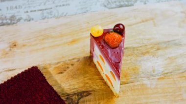 Çilekli, beyaz ve kırmızı kirazlı bir dilim pasta. Pastanın özel bir kubbesi var. Makro ve kaydırma atışı. Arka planda bir retro atmosfer var..