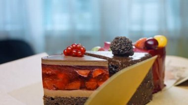 Açık bir kutuda birkaç dilim beyaz ve kırmızı çilekli ve kirazlı pasta ve çikolata. Makro ve kaydırma atışı. Arka planda bir retro atmosfer var..