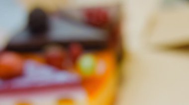 Açık bir kutuda birkaç dilim beyaz ve kırmızı çilekli ve kirazlı pasta ve çikolata. Makro ve kaydırma atışı. Arka planda bir retro atmosfer var..