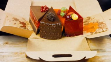 Kadın masaya birkaç dilim beyaz ve kırmızı çilek ve kirazlı pasta ve çikolatayı açık bir kutuya koyar. Makro ve kaydırma atışı. Arka planda bir retro atmosfer var..