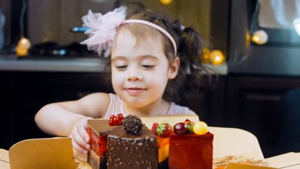소녀는 상자에서 빨간색의 딸기와 케이크와 초콜릿을 조각먹는다 매크로와 슬라이더 배경에는 — 비디오