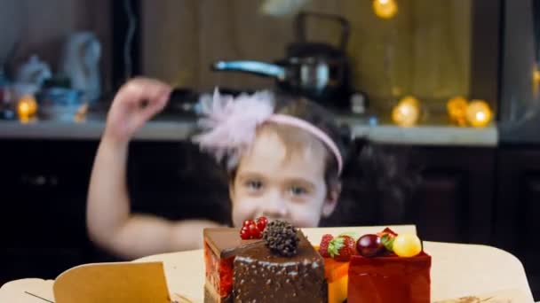 소녀는 상자에서 빨간색의 딸기와 케이크와 초콜릿을 조각먹는다 매크로와 슬라이더 배경에는 — 비디오