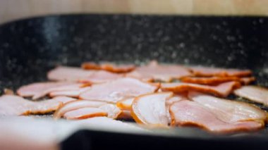 Aşçı kızarmış pastırmayı kaşıkla karıştırır. Kamera ızgarada pastırma pişirmeyi takip ediyor..