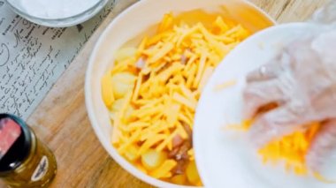 Kadın salataya marine edilmiş çedar peyniri koyuyor. Jalapeno biberi, jambonlu patates salatası. Yirmili yılların modasına uygun yemekler..