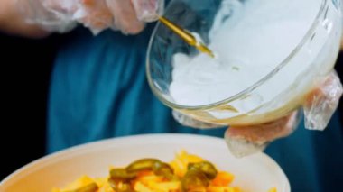 Kadın salata kasesine mayonez koyuyor. Jalapeno biberi, jambonlu patates salatası. Yirmili yılların modasına uygun yemekler..